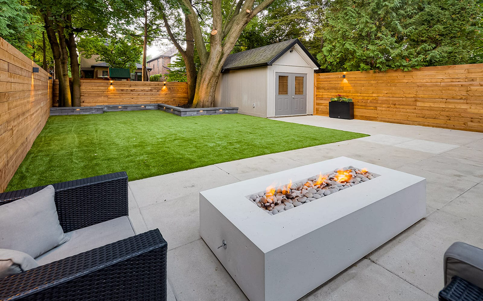 Complete Toronto Landscaping Project; Featuring Small Retaining Wall, Composite Deck Build with Stainless Steel Glass Railings, Interlocking & Outdoor Fireplace by Toronto Landscaping Company.