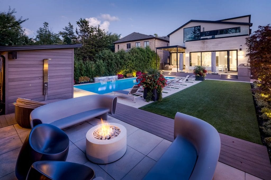 Toronto Landscape Design and Construction Project, Featuring Outdoor Lighting, Pool with Swim Spa and Water Feature Installation, Stone Interlocking, Outdoor Fireplace, and Woodworking Cabana